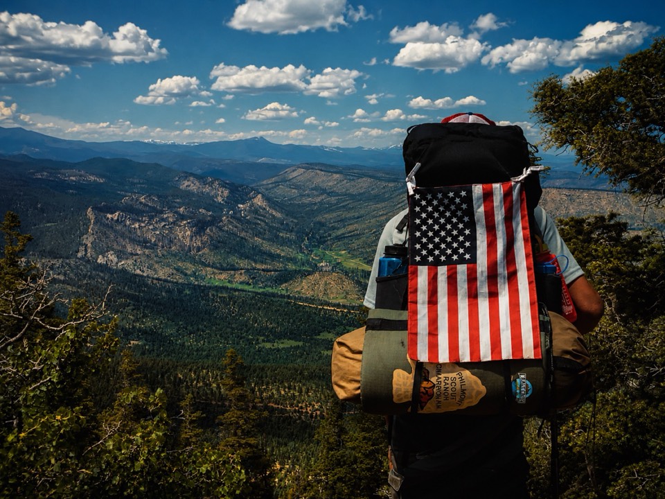 A hiker with a backpack looking out over a wide canyon